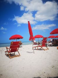 Deck chairs on beach against sky