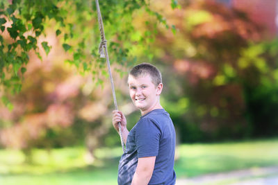 Portrait of boy standing against trees