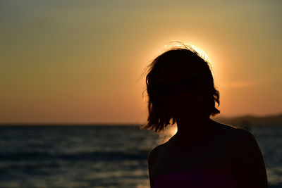 Silhouette woman looking at sea during sunset