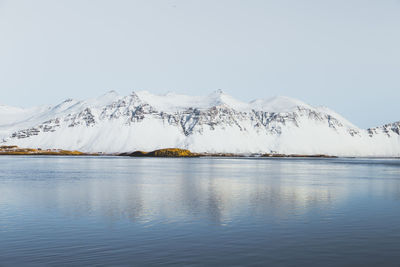 Scenic view of lake against snowcapped mountains against clear sky