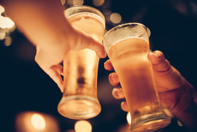 Cropped hands of people toasting beer glasses in bar