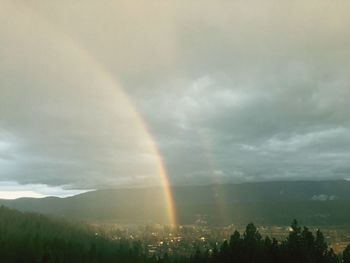 Scenic view of rainbow over landscape against sky