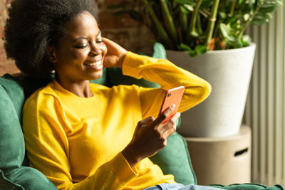 Woman using mobile phone while sitting at home