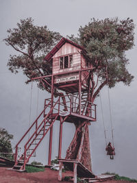 Low angle view of house by trees against sky