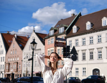 Portrait of woman standing against buildings in city