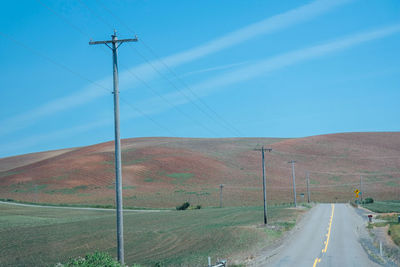 Road by landscape against blue sky