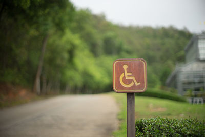 Empty road by disabled sign on field