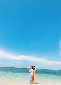 Portrait of smiling women standing at beach against sky