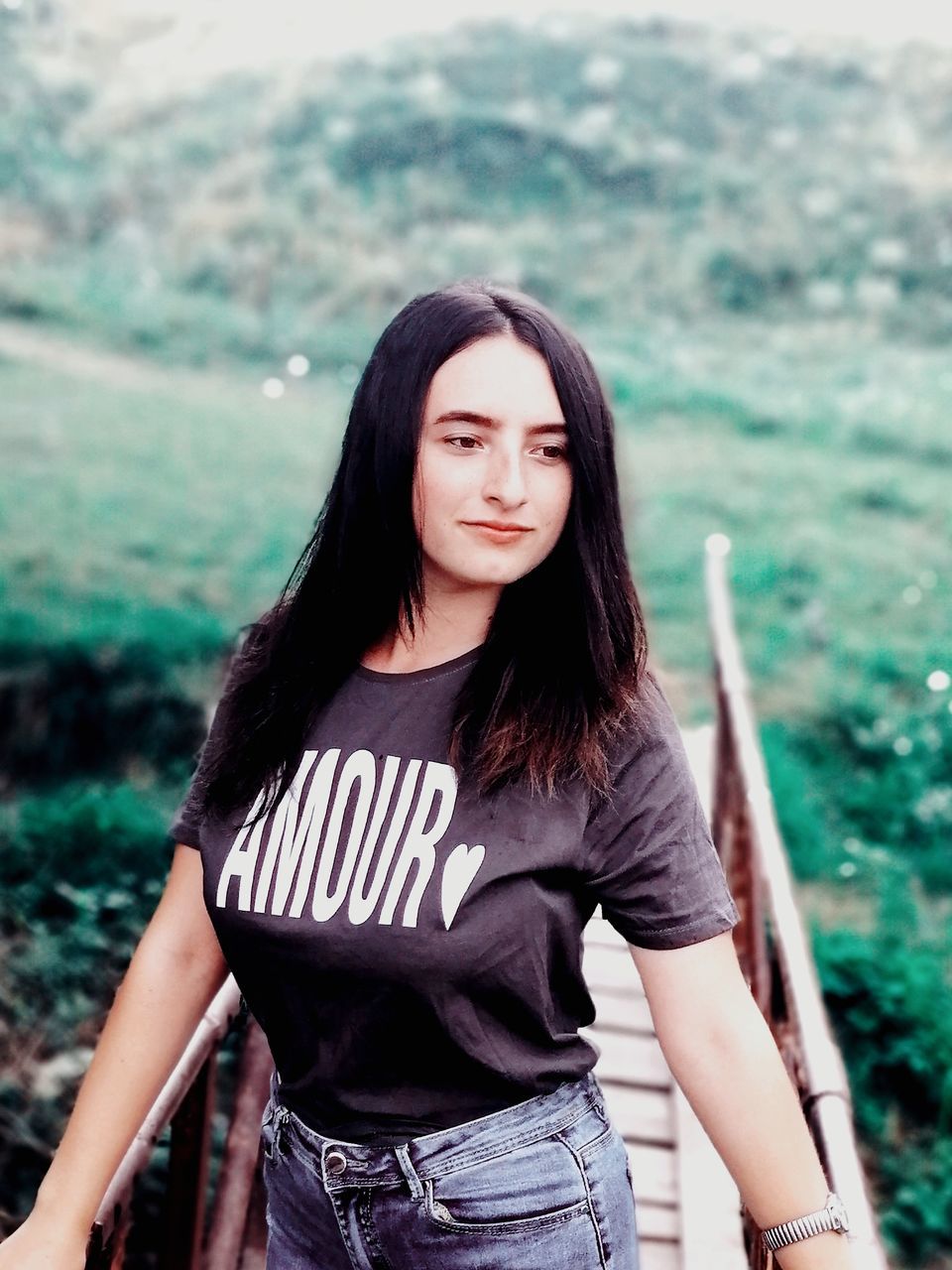 PORTRAIT OF A SMILING YOUNG WOMAN STANDING AGAINST THE BACKGROUND