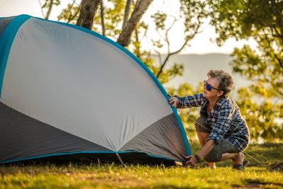 Woman pitching tent on field