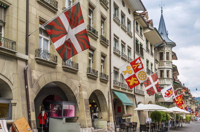 Low angle view of flags hanging on street amidst buildings in city