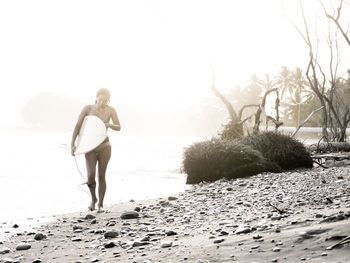 Woman with surfboard walking at beach