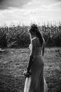 Rear view of woman standing on field against sky