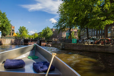 Boats in canal by city against sky