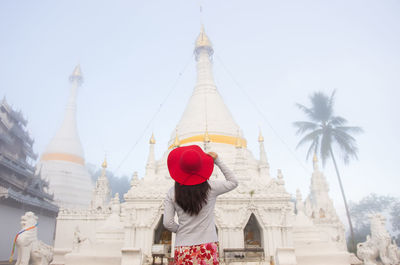 Rear view of woman standing outside temple against building