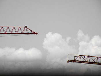 Low angle view of crane against bridge against sky