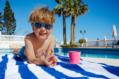 Portrait of young woman wearing sunglasses on bed at home