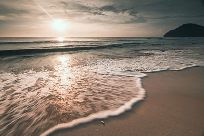 Long exposure shot soft wave of the sea on the sandy beach at morning sunlight, nature landscape 