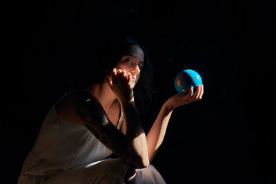 Young woman looking away against black background