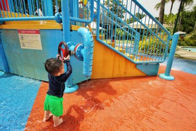 Rear view of boy playing on slide at playground