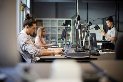 Male entrepreneur using laptop at desk in creative office