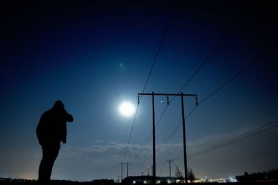 Low angle view of silhouette man standing against blue sky