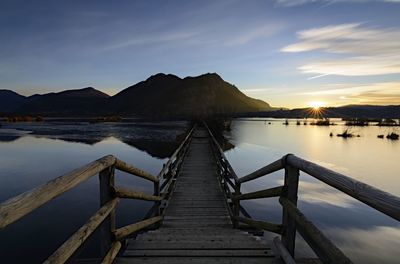 Wooden pier over lake against sky during sunset