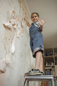 Portrait of boy with arms raised against wall