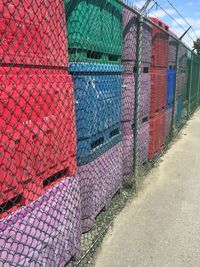 Multi colored chainlink fence against sky