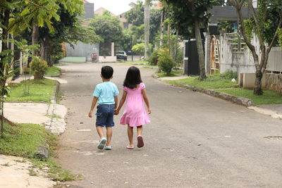 Rear view of  boy and girl walking on street