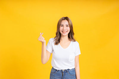 Portrait of a smiling young woman against yellow background