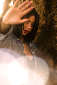 Portrait of young woman with tree trunk