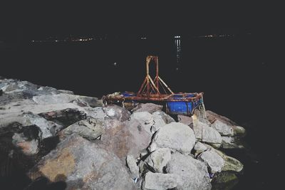 Rocks by sea against sky at night