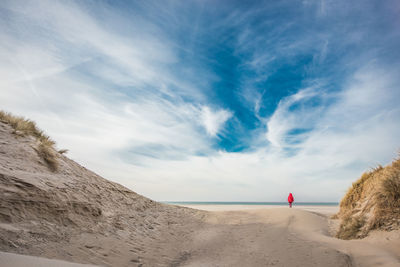 Mid distance of woman walking at beach against sky