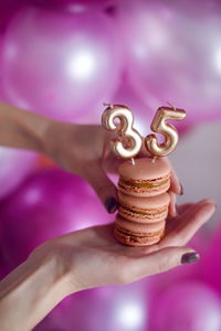 Woman's hand with manicure holding cookies with candles numbers 35