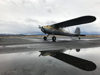 Airplane on airport runway against sky during rainy season