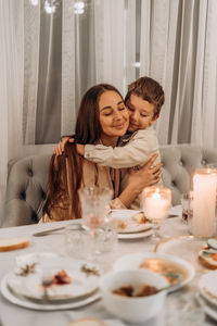 Portrait of smiling mother and daughter sitting at home