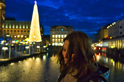 Side view of thoughtful woman looking away in illuminated city at night