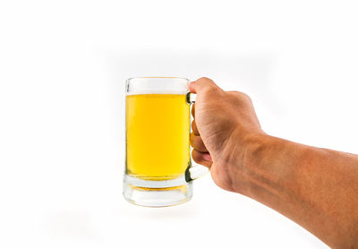 Close-up of hand holding beer glass against white background