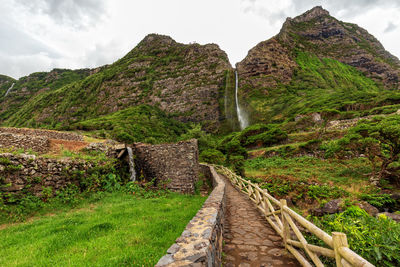 Walkway leading towards mountain against sky