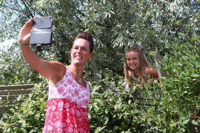 Happy mother and daughter taking selfie through mobile phone at park