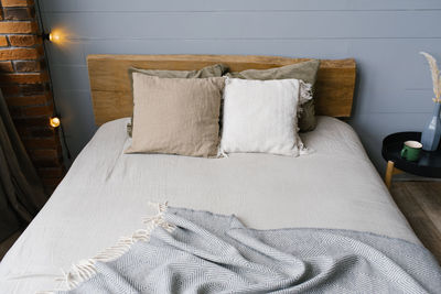 A modern scandinavian grey bedroom with pastel-colored bedding and pillows. wooden bed