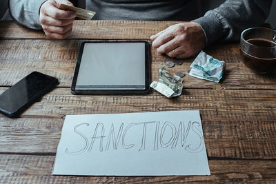 Midsection of man using digital tablet on table