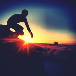 Silhouette man against sea during sunset