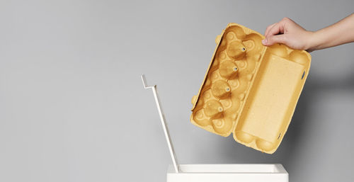 Close-up of person holding ice cream over white background