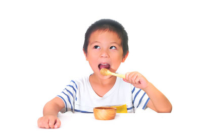 Portrait of cute boy eating food against white background