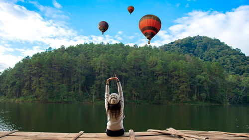 Hot air balloon flying over lake against sky