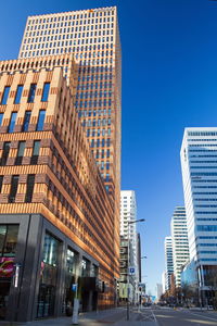 Low angle view of buildings against clear blue sky in city