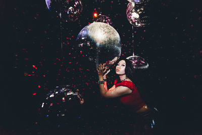 Portrait of woman holding balloons at night