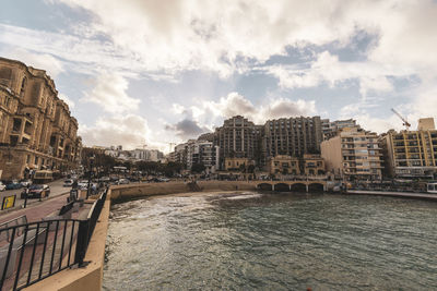 Buildings by river against sky